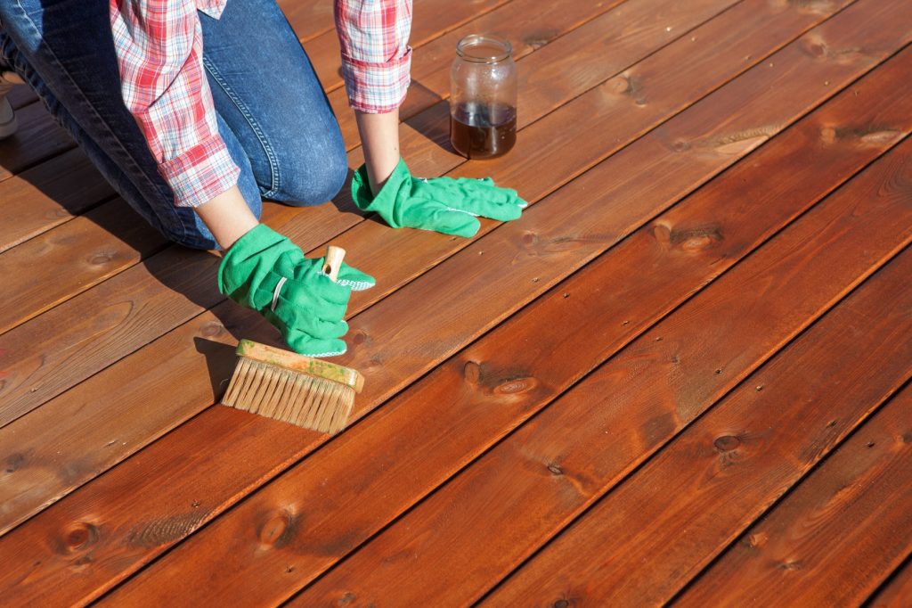 lady staining wooden decking